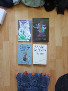 Four books lying flat on a hardwood floor.